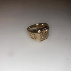 Äkta silverring, 8K pläterad. Örnmotiv. - Säljer nu denna fina ring i perfekt skick. Ringen är äkta silver som pläterats med 8K guld. Örnmotiv fram och på sidorna.