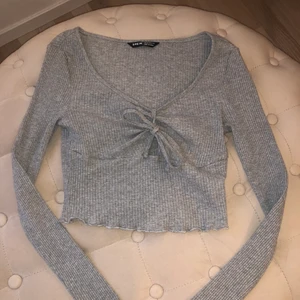 Topp - Fin grå topp med liten rosett på framsidan. Aldrig använt. Frakt betalas av köparen.