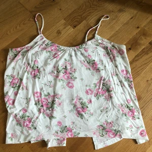 Blommigt linne - Blommigt linne med öppen rygg. Ryggen är skuren och har två snören som man kan låta hänga eller knyta till en rosett. Storlek M 