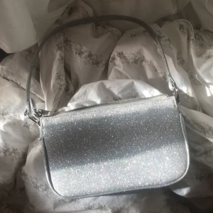 Glitter axelväska💖 - Säljer denna väskan från Gina tricot. Köpt för 280kr. Tanken va att använda den på nyår men det gjorde jag aldrig. Och inser nu att den inte kommer komma till någon användning. Buda i kommentarerna. Köpare står för frakten💖