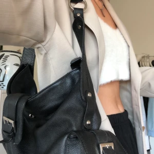 Cool väska i konstläder - Assnygg, rymlig svart väska i troligtvis konstläder thriftad i Göteborg. Får plats en liten chromebook. Silverdetaljer. Märket har suddats bort. BUD TILL ONSDAG 10/2. 135kr ligger budet på just nu.