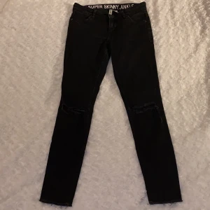 Jeans från H&M strl 34 - Tighta lågmidjade jeans med hål på knäna (syns dåligt på bild) från H&M, Divided i storlek 34 🖤🖤 Ganska hårda i materialet. Jeansen är i fint skick och är sparsamt använda. Samfraktar gärna med andra plagg och betalning sker via Swish <33