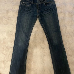 Mörkblå jeans från Orsay - Snygga mörkblå jeans från Orsay med klassisk femficksdesign och kontrastsömmar. De har en saknad knap det ska vara 2 men det går att få av mig - och dragkedjestängning framtill och en bekväm passform. Perfekta för en avslappnad stil. Low waist flare vintage 2000 jeans 