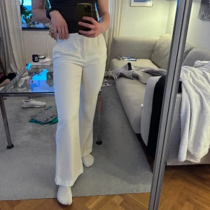 Vita kostymbyxor med hög midja - Snygga vita kostymbyxor med hög midja och bootcut-stil från Zara. Upplevs inte speciellt genomskinliga. Har syttnin de i midjan så passar mig som brukar ha ca strl 38 i byxor!