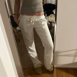 ROXY linnebyxor, Vita  med snörning - Snygga vita byxor med avslappnad passform och snörning i midjan. Perfekta för en bekväm och stilren look. Byxorna har en rak design och är tillverkade i ett lätt material.
