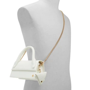 Vit handväska med kedja - Elegant vit handväska med en stilren design och guldfärgad kedja som axelrem. Väskan har ett triangulärt tillbehör fäst vid sidan och är tillverkad i skinn. Perfekt för att ge en lyxig touch till din outfit.