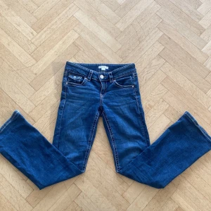 Blå jeans från Gina Tricot - Snygga blå jeans från Gina Tricot med klassisk femficksdesign och knappgylf. Dom är bootcut och lågmidjade. Storlek 158. 