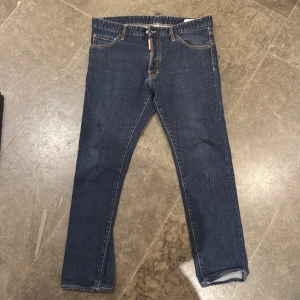 Blå jeans från Dsquared2 - Snygga blå jeans från Dsquared2 med klassisk femficksdesign och gul kontrastsöm. De har en knappgylf och en diskret logga vid gylfen. Perfekta för en stilren look.