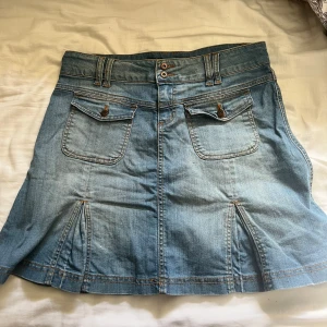 Jeanskjol från ONLY - Snygg jeanskjol från ONLY i klassisk blå denim. Kjolen har en kort längd med fickor fram och bak samt dekorativa sömmar. Perfekt för en avslappnad stil.