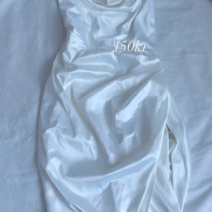 Vit sidenklänning - Elegant vit sidenklänning med en slits på sidan. Perfekt för en stilren look med sin glänsande yta och mjuka material.