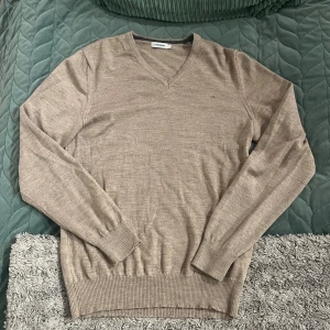 Beige v-ringad tröja från J.Lindeberg - Säljer nu en riktigt fräsch tröja från j-Lindeberg. Den är använd men i bra skick och är perfekt inför våren🙌🏻Storleken är L men passar mer som en M. Vid frågor är det bara att skriva!