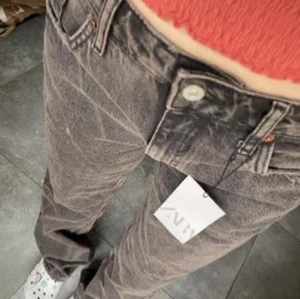 Gråa low waisted jeans - Snygga grå jeansbyxor med en klassisk femficksdesign. Byxorna har en rak passform och är perfekta för en avslappnad stil. De har en knapp och dragkedja framtill.