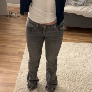Grå jeans från Gina Tricot Young - Snygga grå jeans från Gina Tricot Young med en klassisk femficksdesign. De är low waist bootcut jeans i storlek 170. Lite slitna längst ner på byxan men nästan inget som syns! Pris kan diskuteras 