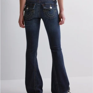 True religon Mörkblå bootcut jeans - Snygga mörkblå bootcut jeans från true religon köpta från Nelly. De e lite slitna längs ner på jeansen men annars inga defekter !💗