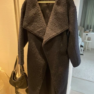 Mörkblå kappa från Gina Tricot - Mörkblå kappa från Gina Tricot. Den har en stor krage och ett bälte i midjan. Nästan aldrig använd. Köptes för ca 700.