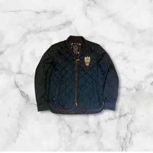 Säljer en stilren svart quiltad jacka från morris Jackan har en dragkedja framtill och långa ärmar. Perfekt för kyligare dagar med sin klassiska design och bekväma passform.