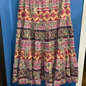 Mönstrad lång kjol från Prêt à Porter - En färgglad, mönstrad kjol från Prêt à Porter med ett unikt mönster i rött, gult och blått. Kjolen har en volangdetalj och en dragkedja i sidan. Pris kan diskuteras