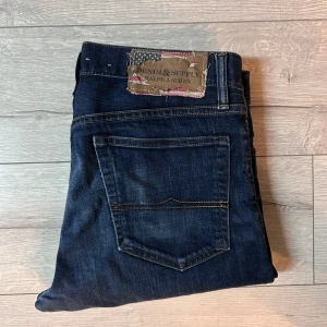 Mörkblå jeans från Ralph Lauren - Snygga mörkblå jeans från Denim & Supply Ralph Lauren med en skinny fit. De har en klassisk femficksdesign och en cool patch med amerikansk flagga på baksidan. Perfekta för en stilren look.