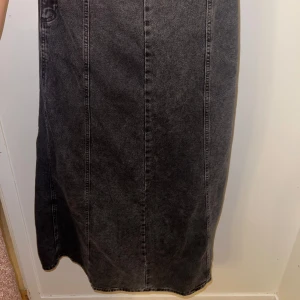 Grå jeanskjol - Snygg grå jeanskjol i lång modell med en diskret slits framtill. Kjolen har en klassisk design med synliga sömmar som ger en stilren look. Perfekt för en avslappnad stil. Pris kan diskuteras. Frakt står för köparen