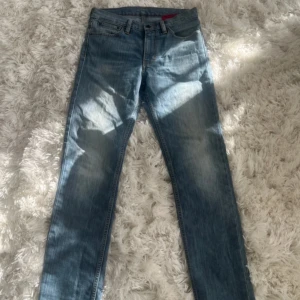 Blå jeans från Levi's - Snygga blå jeans från Levi's med klassisk femficksdesign och en bekväm passform. De har en traditionell knappgylf och är perfekta för en avslappnad stil. Levi's ikoniska lädermärke syns på baksidan.