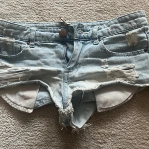 Ljusa jeansshorts med slitningar - Säljer ett par ljusa jeansshorts med coola slitningar och fransiga kanter. De har en knapp och dragkedja framtill samt fickor både fram och bak. Skulle säga att de sitter som xs/32/24. Pris kan diskuteras vid snabb affär! 