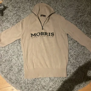 Beige tröja från Morris - Säljer en beige tröja från Morris med dragkedja och ribbade detaljer. Tröjan har en stilren design med text på framsidan. Perfekt för en avslappnad stil. Nypris 2000. Använd 1-2 gånger.