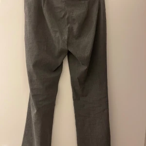 Grå byxor från Nelly - Snygga grå byxor från Nelly med en klassisk design. De har en rak passform och är perfekta för en stilren look. Byxorna är tillverkade i ett bekvämt material som passar bra till olika tillfällen.