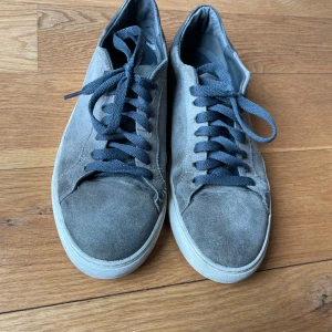 Grå Axel Arigato clean 90 suede - Snygga Axel arigato sneakers i grå mocka och vit sula. Skorna har en klassisk låg profil och rund tå, perfekt för en clean och stilren look. Mockan är lite sliten men helt nya skosnören som går att köpa nya om man inte gillar färgen. Säljer skorna då de är för små för mig. tror ny pris går för runt 2500kr. tveka inte på att fråga! 😁
