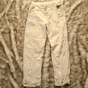 Beiga  Byxor i linnemix från Kappahl, stl 170 - Snygga beiga byxor från Kappahl i storlek 170. 55% lin 45% Bomull. De har elastisk midja bak, knapp och dragkedja framtill samt sidfickor. Byxorna är raka i modellen och tillverkade i ett mjukt tyg som känns skönt mot huden.