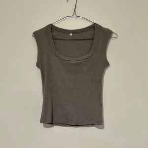 Grå ärmlös linnetopp med rund hals - Grå ärmlös linnetopp med rundad halsringning. Toppen är i mjuk bomull och har en enkel, clean look som passar till allt. Perfekt att styla med jeans eller kjol!🪅