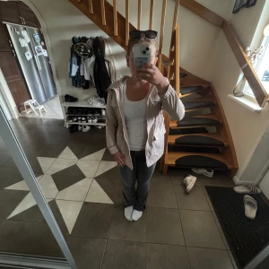 Beige kappa med huva - Säljer en stilren beige vindjacka med huva och dragkedja framtill. Jackan har en enkel design med resår vid ärmsluten och praktiska fickor. Perfekt för dig som vill ha en lätt jacka till vår eller sommarkvällar. Den är dock nåra jätte små fläckar, men man ser de inte alls tydligt när man har på sig den.