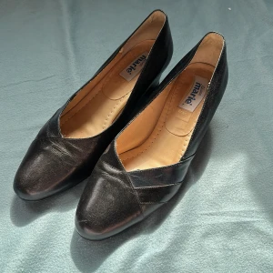 Svarta vintage klackar - Klassiska svarta klackar från Sköna Marie, storlek 6½ (motsvarar ca EU 39). Bred modell – perfekt för dig som vill ha lite extra komfort! Troligtvis från 80-/90-talet, i äkta retrostil. Fint skick, knappt använda. Säljes pga fel storlek 💔