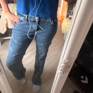 Blå bootcut jeans med coola sömmar - Säljer ett par blå jeans med bootcut-modell och snygga detaljerade sömmar över benen.