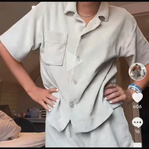 Ljusgrön kortärmad pyjamas  - Säljer en ljusgrön pyjamas med kort ärm och avslappnad passform. Skjortan har klassisk krage, knäppning framtill och en stor bröstficka. Materialet ser ut att vara mjukt och lite tjockare.