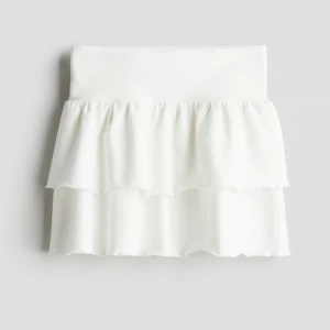 Vit volangkjol  - Supersöt vit kortkjol med dubbla volanger och låg midja. Kjolen har en flowy känsla och är perfekt för en fräsch och trendig look. Passar till allting.