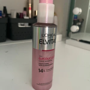 L'Oréal Elvital Glycolic Gloss Serum - L'Oréal Elvital Glycolic Gloss Leave-In Serum i en snygg rosa flaska med silvrig detalj. Serumet ger glans och täcker hårstråna för en riktigt glansig finish. Perfekt för dig som vill boosta hårets lyster och minska friss. Innehåller 14% gloss complex.