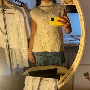 Stickad ärmlös polotröja i beige - Säljer en chunky stickad polotröja i beige med grovt mönster. Tröjan är ärmlös och har hög krage🧸🧸