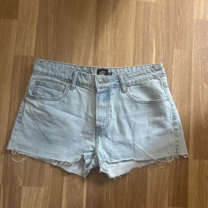 Low Waist Jeansshorts - Ljusblå Low Waist Jeansshorts med knappar Modellen Lexi, från sommarkollektionen 2023 Använda fåtalet gånger (ca 2ggr) Från Lager157