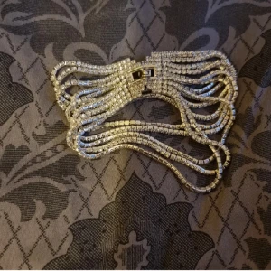 silverfärgat armband - Ett riktigt statement-armband med flera rader glittrande stenar i silverfärg. Armbandet har en bred design och stängs med ett snyggt spänne. Endast provad.