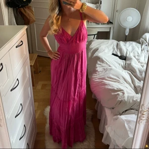 Rosa långklänning med broderi - Superfin rosa långklänning med smala axelband, omlott-v-ringning och broderade detaljer upptill. Klänningen har resor och även ett knytband i ryggen. Tyvörr har den en liten fläck som jag inte vet om den går att få bort, jag har inte försökt, se sista bild.💞 säljer då den är för stor på mig.