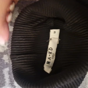 Svart ribbad långärmad tröja NA-KD - Svart ribbad långärmad tröja från NA-KD i storlek M. Tröjan har en figurnära passform och är tillverkad i ett stretchigt material som sitter snyggt på kroppen. Perfekt att styla med jeans eller kjol för en clean look.