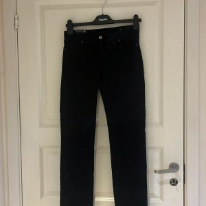 Svarta jeansbyxor från Åhléns - Säljer ett par svarta jeansbyxor från Åhléns med klassisk femficksdesign och raka ben. Byxorna har normal passform och är tillverkade i ett stretchigt material för extra komfort. Perfekta till många olika outfits.
