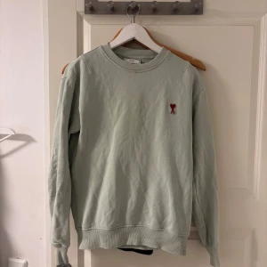 Ami paris sweatshirt  - Säljer en ljusgrön sweatshirt från Ami med rund hals och broderad röd hjärtlogga på bröstet. Fin och fräsch nu till sommaren, pris kan diskuteras vid snabb affär. Säljer för den är för liten för mig