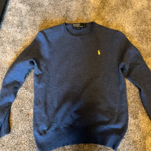 Mörkblå tröja från Ralph Lauren - Säljer en klassisk mörkblå tröja från Ralph Lauren med rund halsringning och den ikoniska loggan broderad på bröstet. Perfekt till både jeans och chinos för en stilren look. Pris kan diskuteras 