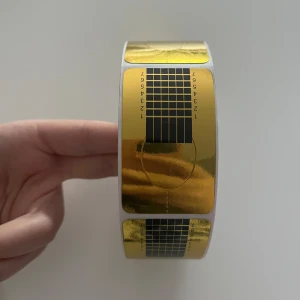 Nagelformar i guld för förlängning - En stor rulle med självhäftande nagelformar i guld och svart, perfekta för att bygga och forma konstnaglar. Varje form har tryckta linjer och siffror för exakt applicering och längd. Passar både gelé och akryl.