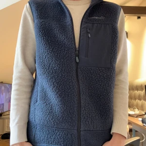 Blå fleeceväst från Norrøna - Säljer en snygg blå fleeceväst från Norrøna med dragkedja och bröstficka. Perfekt för lager-på-lager under kyliga dagar. Västen har en stilren design med broderad logga på bröstet och ryggen.Säljer då den inte passar mig, lite för stor. Hör gärna av dig vid funderingar! Mvh Rufus 😄 