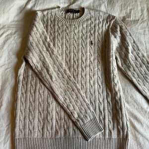 Beige kabelstickad tröja från Polo Ralph Lauren - Säljer en beige kabelstickad tröja från Polo Ralph Lauren i storlek S men passar även M. Helt ny och oanvänd. 