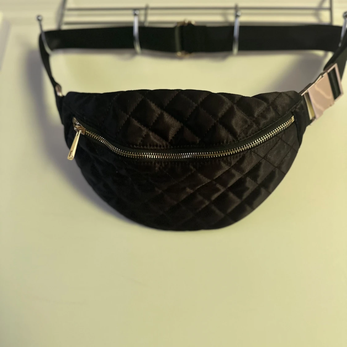 Svart quiltad magväska med gulddragkedja