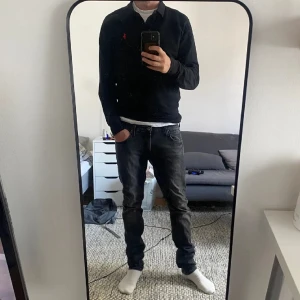 långärmad pikétröja från Polo Ralph Lauren - Svart långärmad pikétröja från Polo Ralph Lauren med klassisk krage och knappar framtill. Tröjan har röd broderad logga på bröstet och är i slim fit stretch mesh-material. Hör av dig vid någon fundering så löser vi en deal🤝.