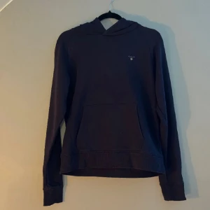 Gant Hoodie mörkblå - Mörkblå hoodie från Gant med klassisk i okej skick. Den är i storlek 176. Och passar som Xs till S i vuxenstorlek.